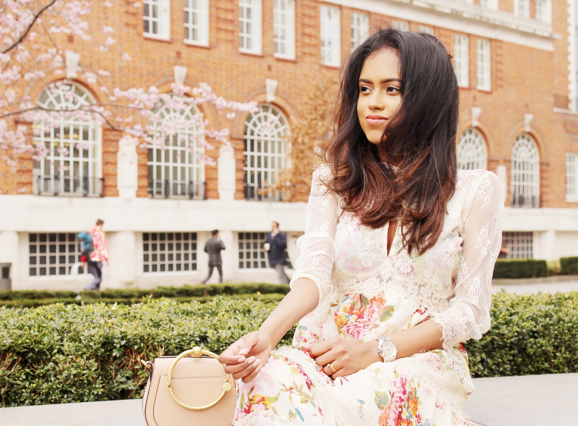 Sachini sitting wearing a floral dress with a Chloé bag