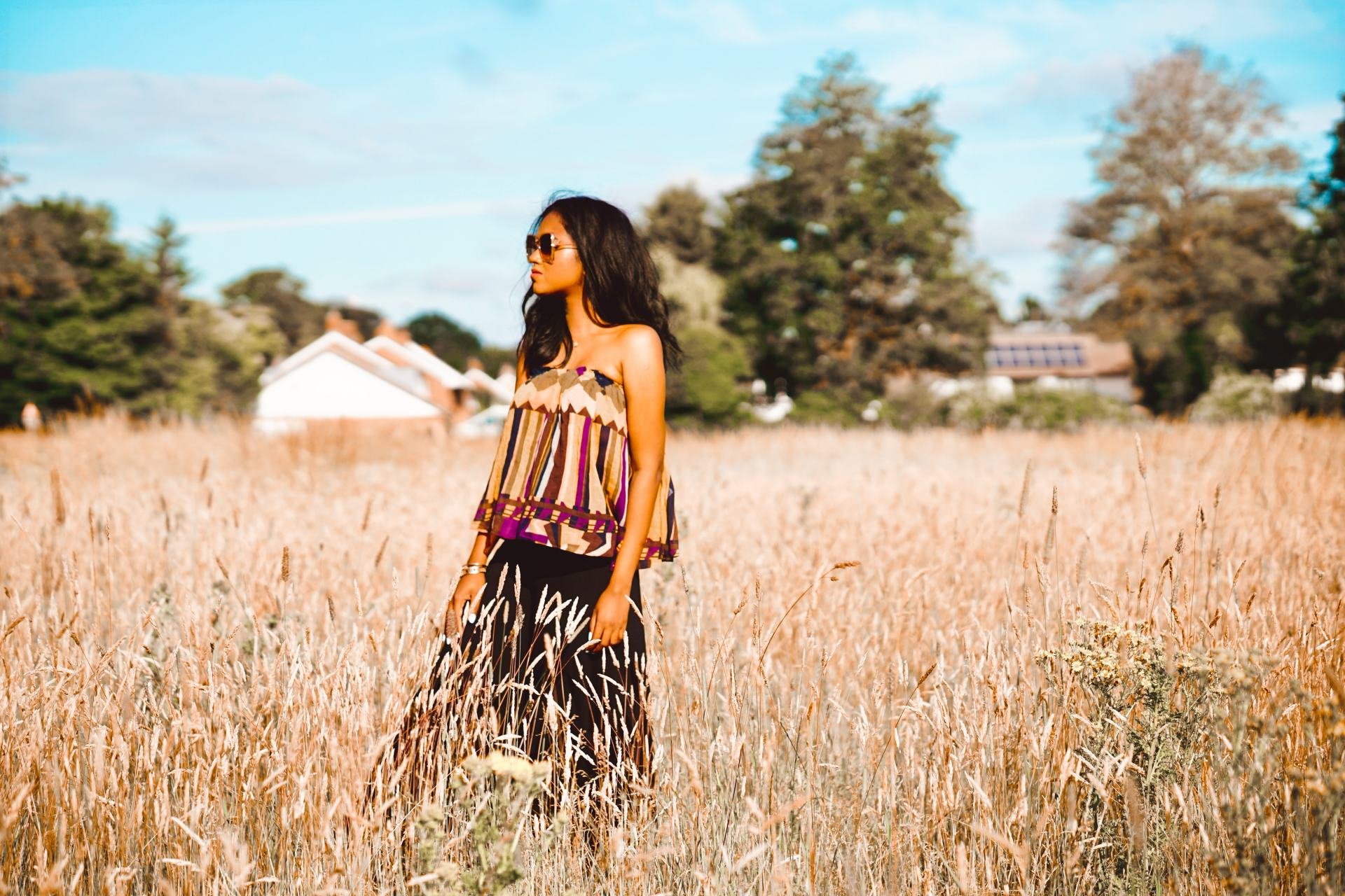 Sachini wearing a Bash dress standing in a field of wheat