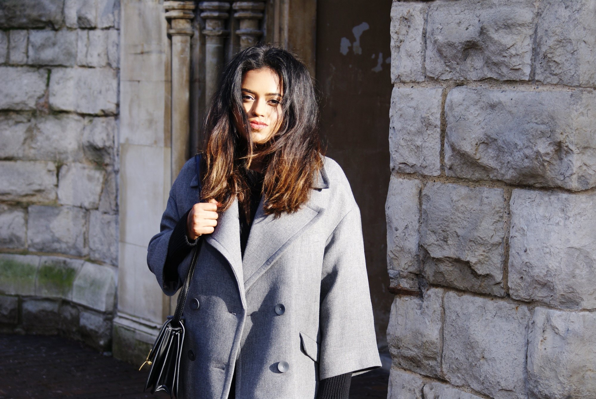 Sachini wearing a grey coat with a black bag