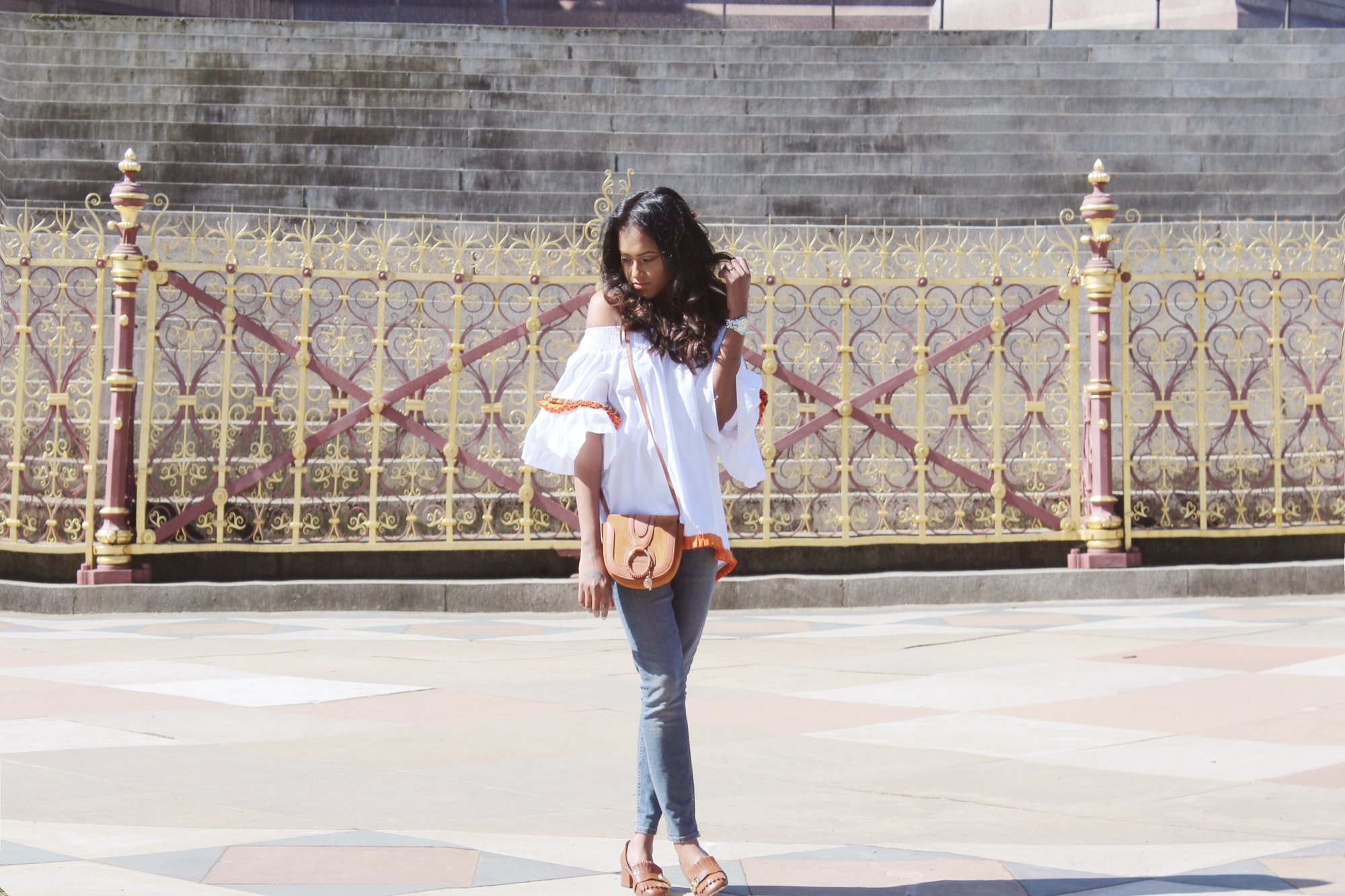 Sachini wearing a white top, blue jeans, brown Gucci shoes with a brown handbag