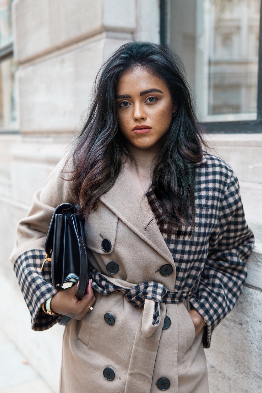 Close up of Sachini wearing a QUAINT Josephine Coat holding a black Dior saddle bag