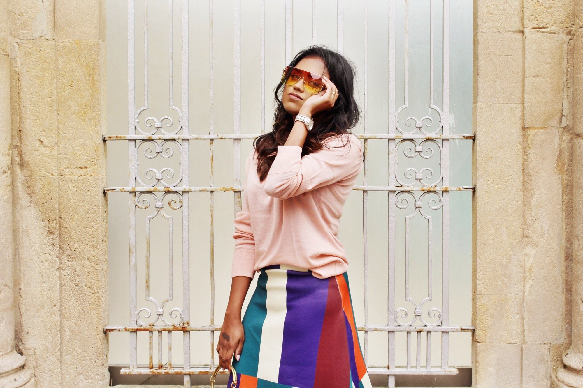 Sachini wearing sunglasses, a pink top and a colour blocked skirt