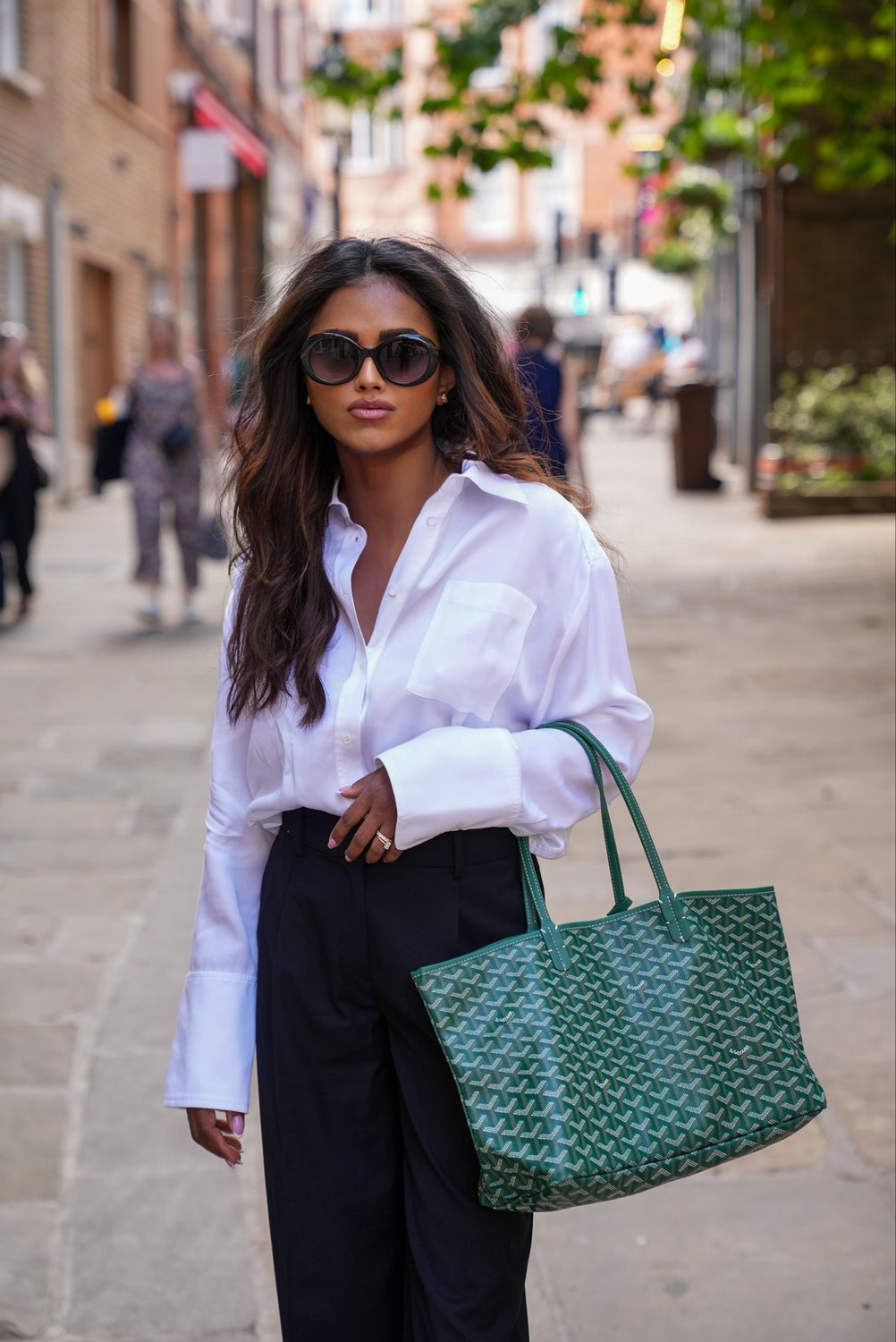 Sachini Dilanka wearing a crisp white shirt and a green Goyard bag