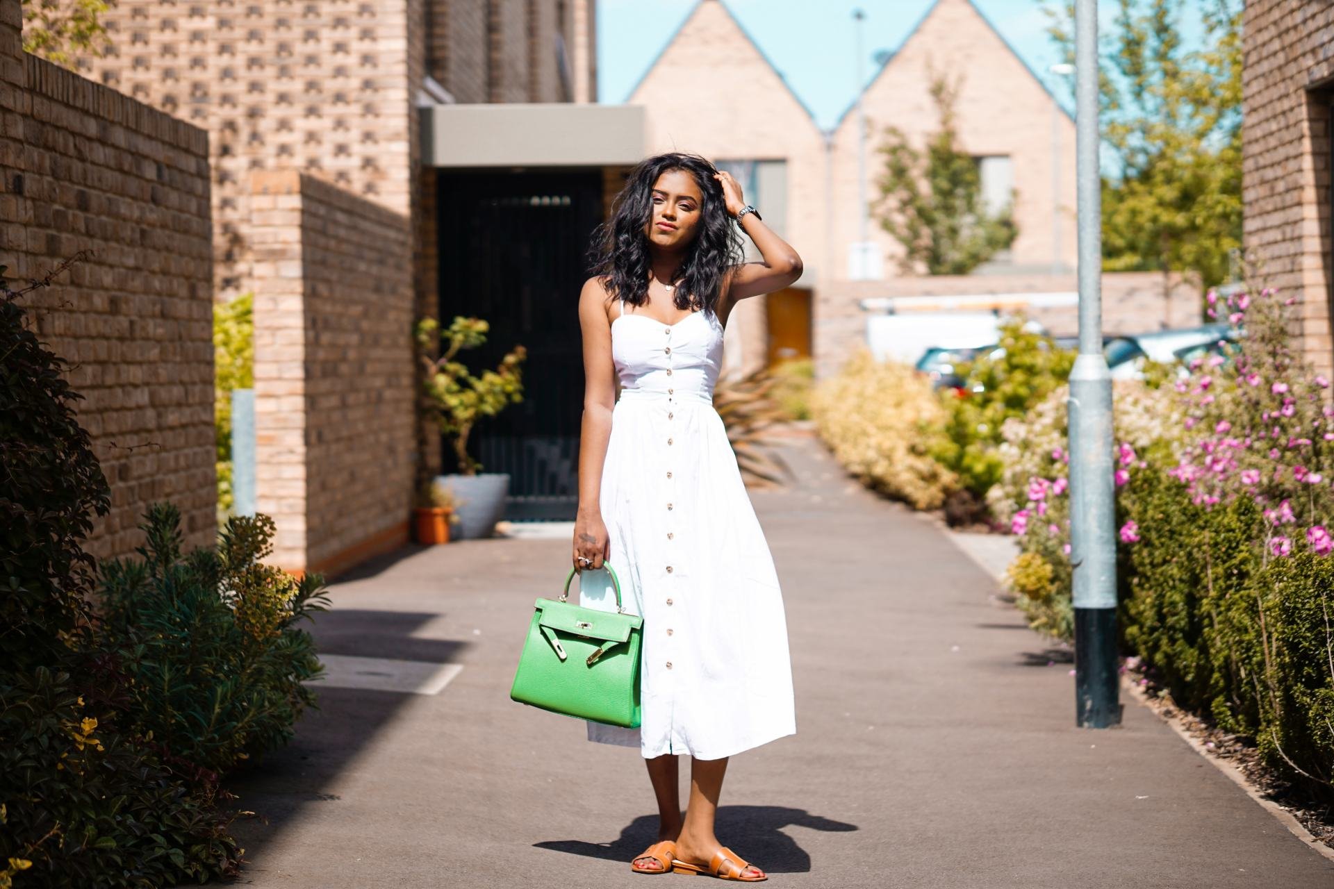 Sachini wearing a white dress holding green bag