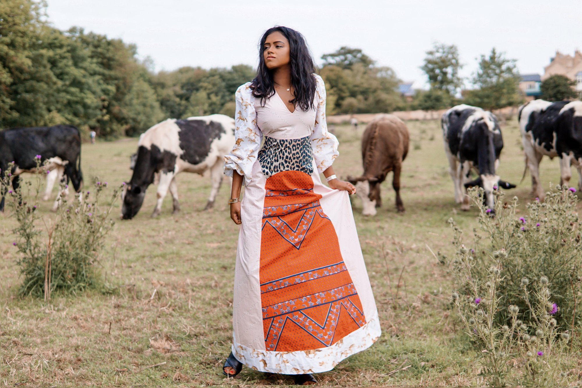 Sachini wearing a Ganni dress with cows in the background