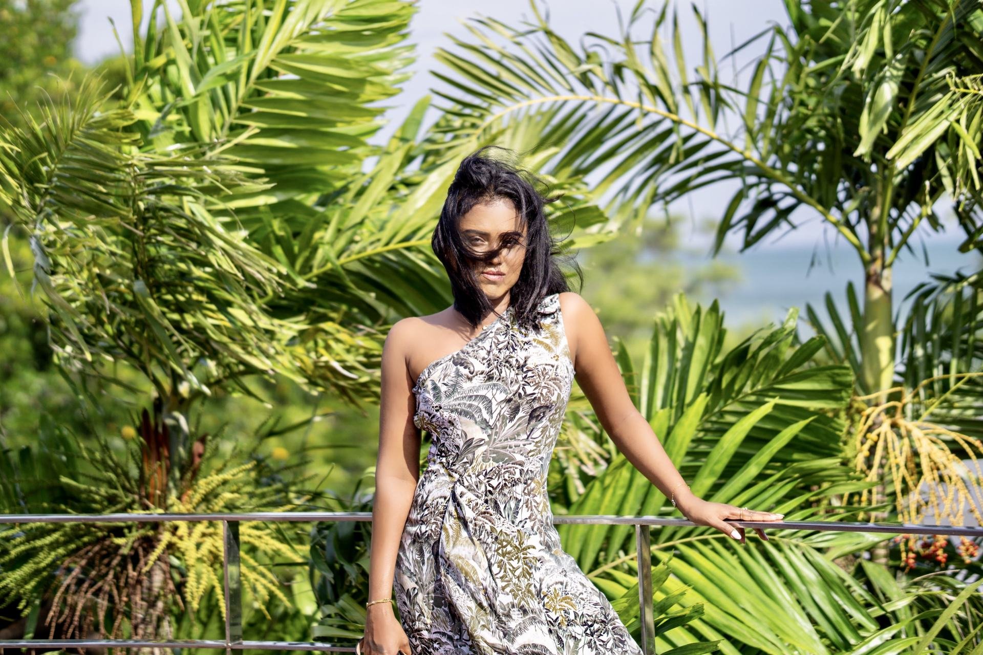 Sachini wearing a white and green Reiss dress with  exotic trees in the background